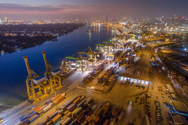 Aerial view of a river port, container terminals and an illuminated city at dusk