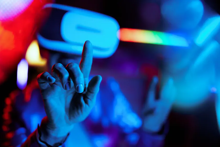 Person using a virtual reality headset and reaching forward in electric blue and red light