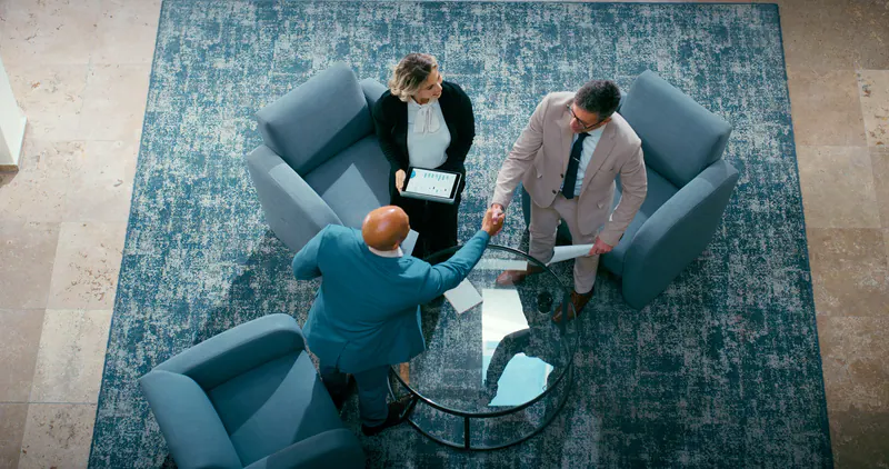 Businesspeople greeting with a handshake during a meeting, viewed from above